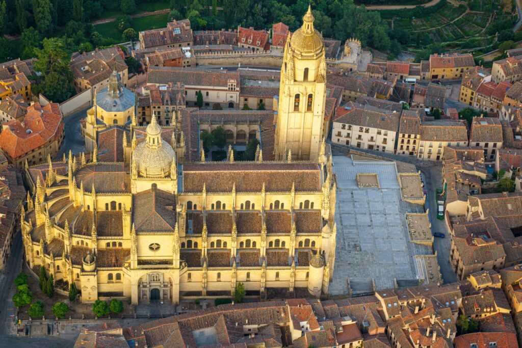 Stunning aerial shot of Segovia Cathedral surrounded by historic buildings at dusk.