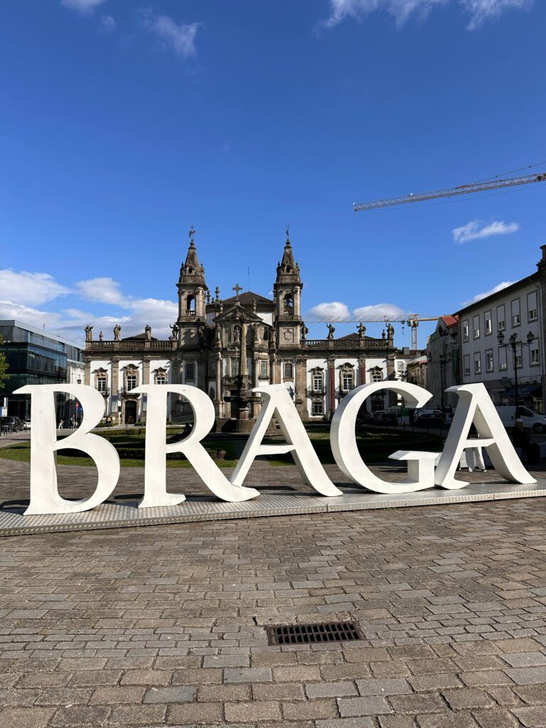 Braga sign with historic church under blue sky, showcasing Portugal's rich architectural beauty.