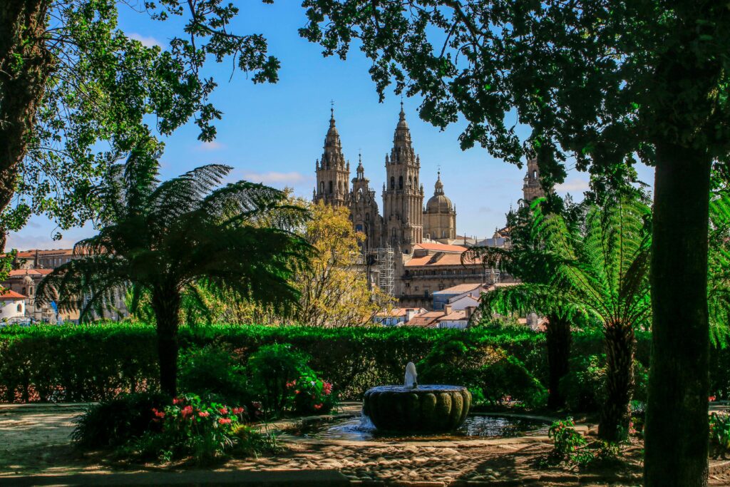 Lush park view of Santiago de Compostela Cathedral amidst trees and greenery.